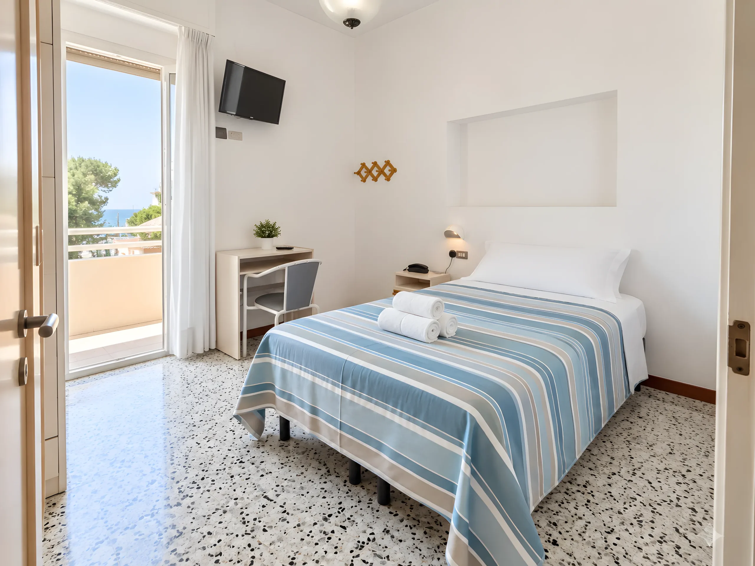 Chambre double avec lit bleu et porte-fenêtre sur le balcon