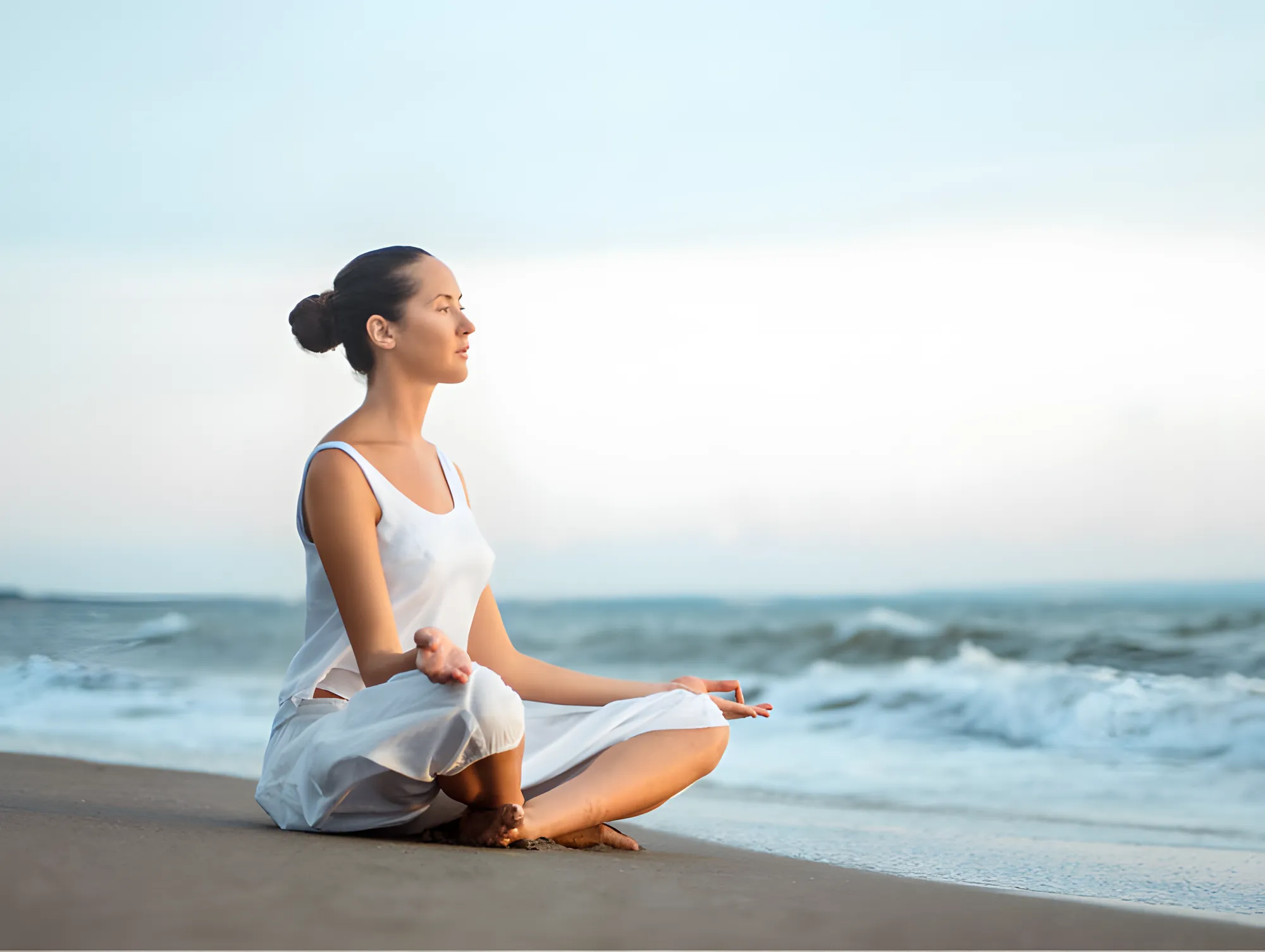 Une femme en méditation sur la plage, face à la mer